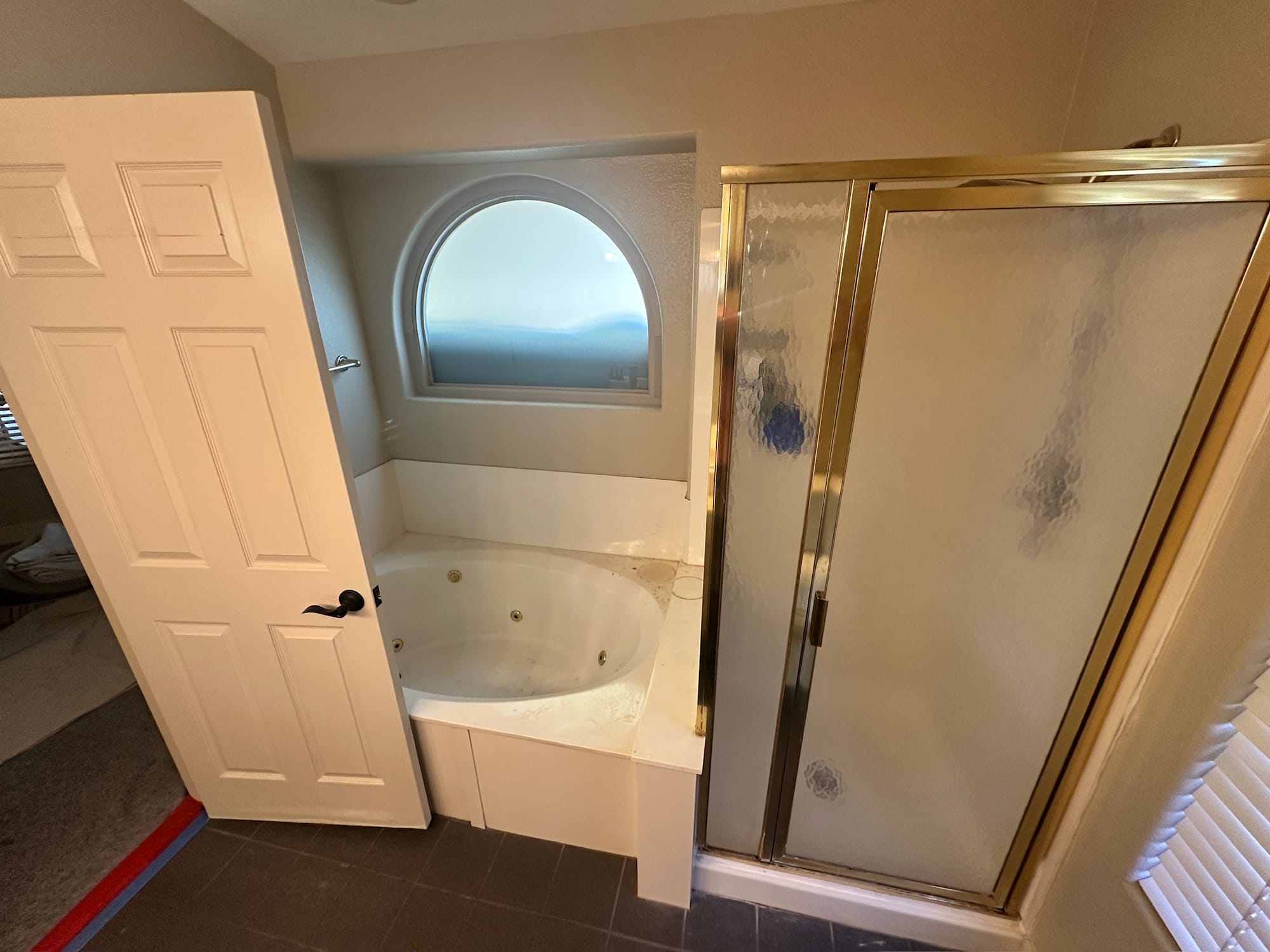 Ahwatukee master bathroom before — 1980s garden tub and gold-framed shower stall under the arched window