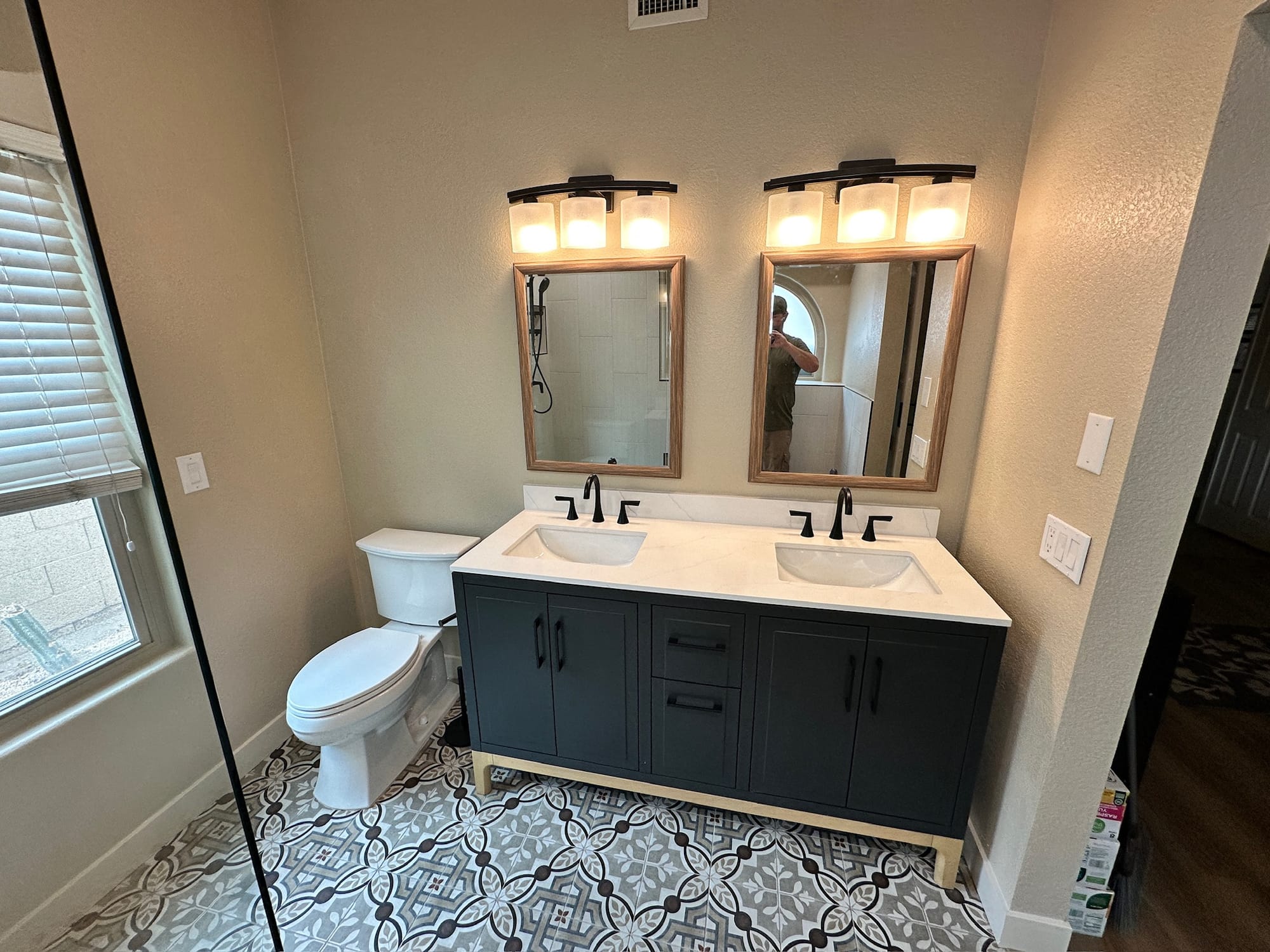 Ahwatukee bathroom — new vanity at an angle showing toilet, framed mirrors, and patterned tile floor
