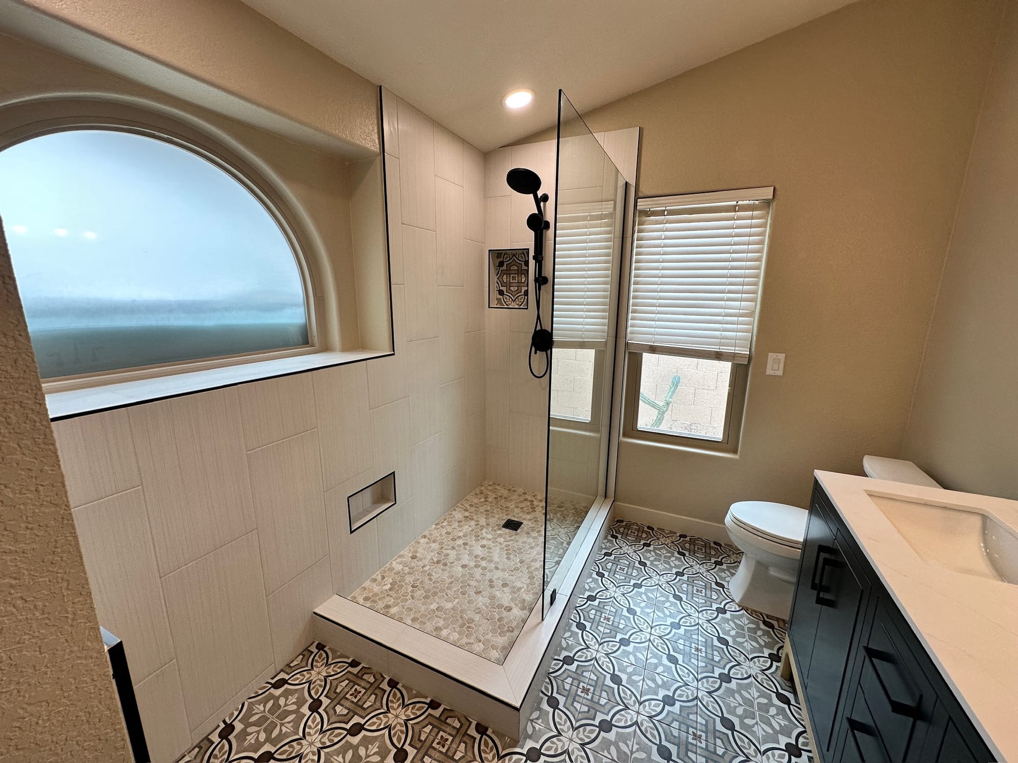 Ahwatukee bathroom — extended walk-in shower with vertical tile, matte black fixtures, niche, and pebble floor