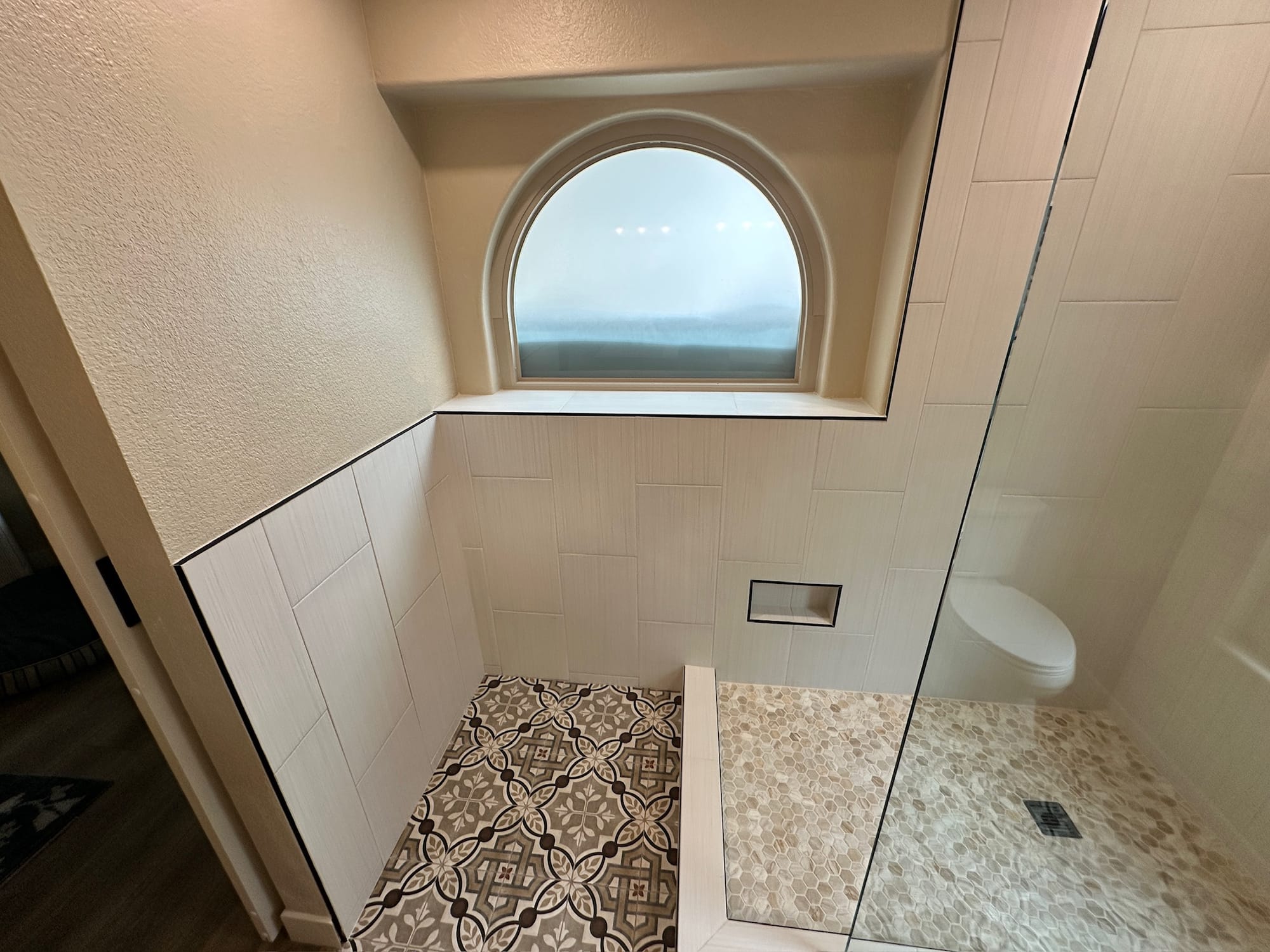 Ahwatukee bathroom — preserved arched window above the new shower wall with patterned tile floor