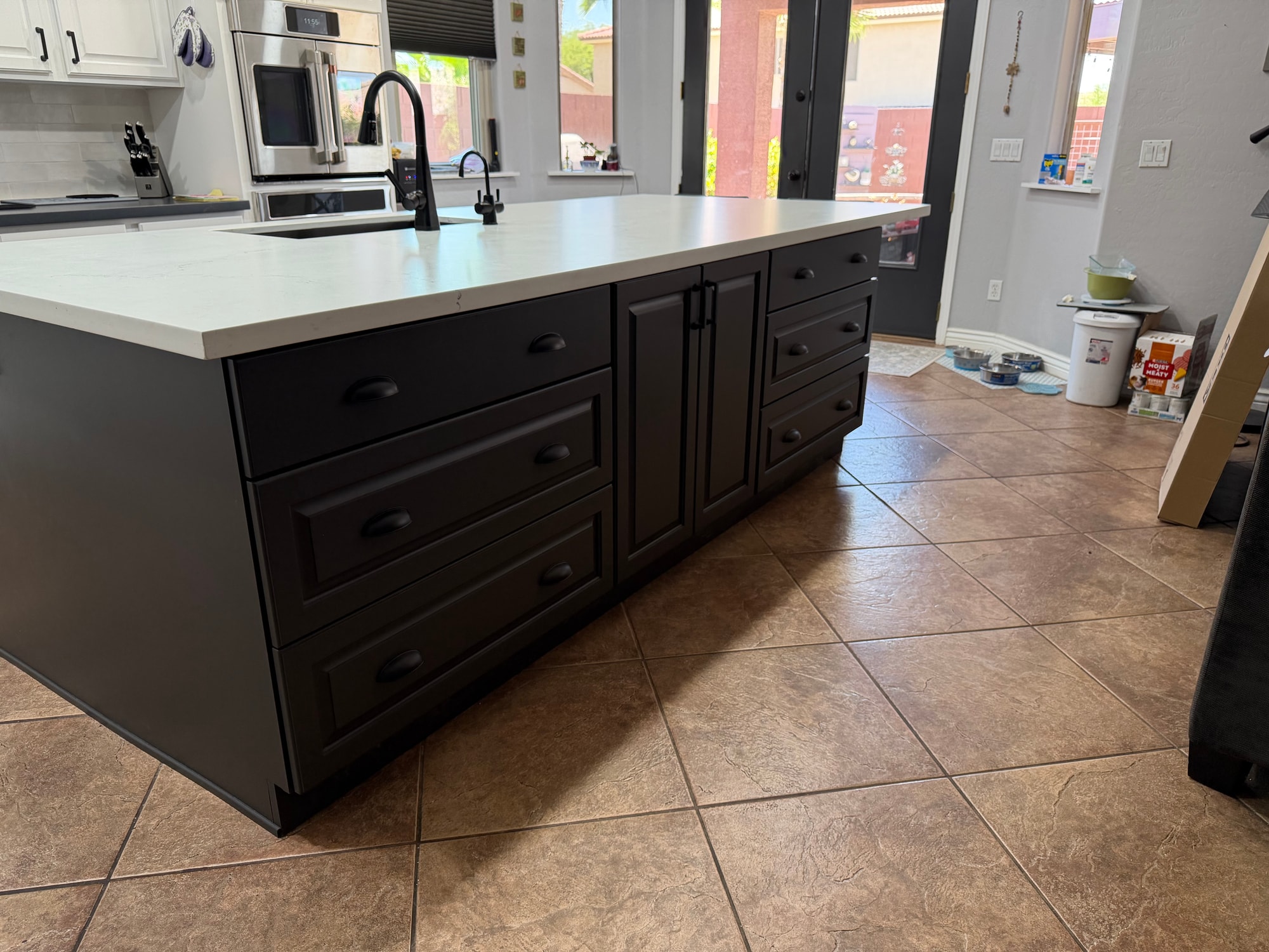 Chandler kitchen after — new 10-foot Sollid Custom Series Revere island in Midnight Sun Matte grey with honed quartz countertop, existing white perimeter cabinets preserved, new darker perimeter counters, Arizona Tile Spark Matte White brick-staggered backsplash, Cafe appliance package
