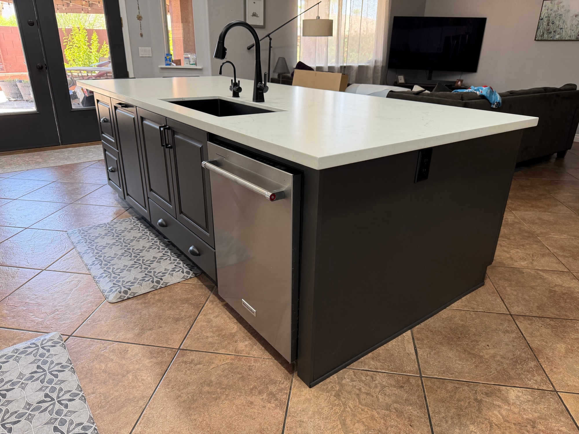 Chandler kitchen after — new 10-foot island with black undermount sink, black Delta pulldown faucet, integrated KitchenAid dishwasher, and the honed quartz countertop running the full length in Sollid Midnight Sun Matte grey