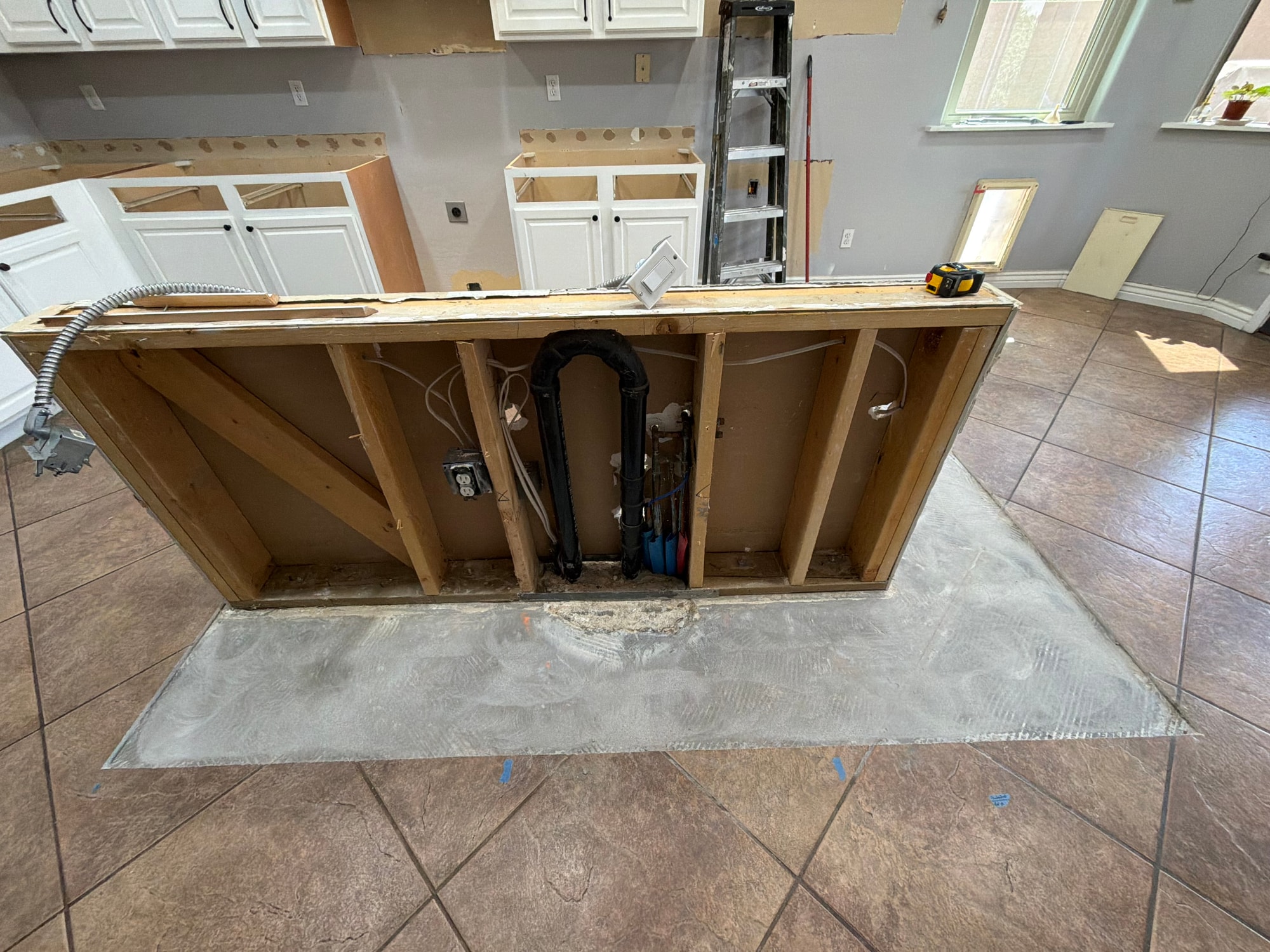 Chandler kitchen before — cook wall during demo with the old island partially removed, laminate counters out, backsplash gone, and plumbing / electrical exposed for the new 10-foot island