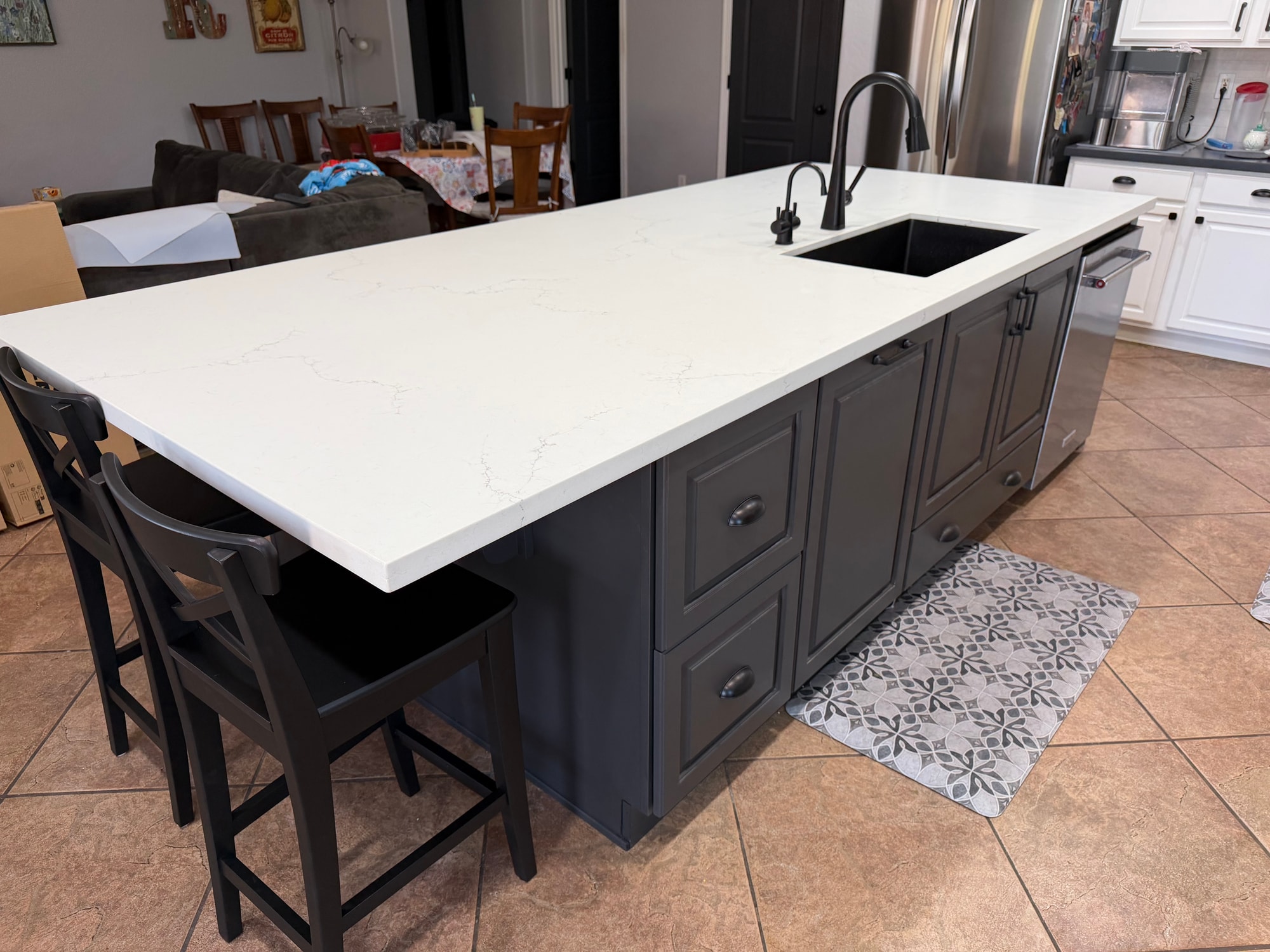 Chandler kitchen — angled wide view showing the full 10-foot double-sided island with drawer storage, bar seating at the far end, and the new Arizona Tile Spark Matte White backsplash on the perimeter
