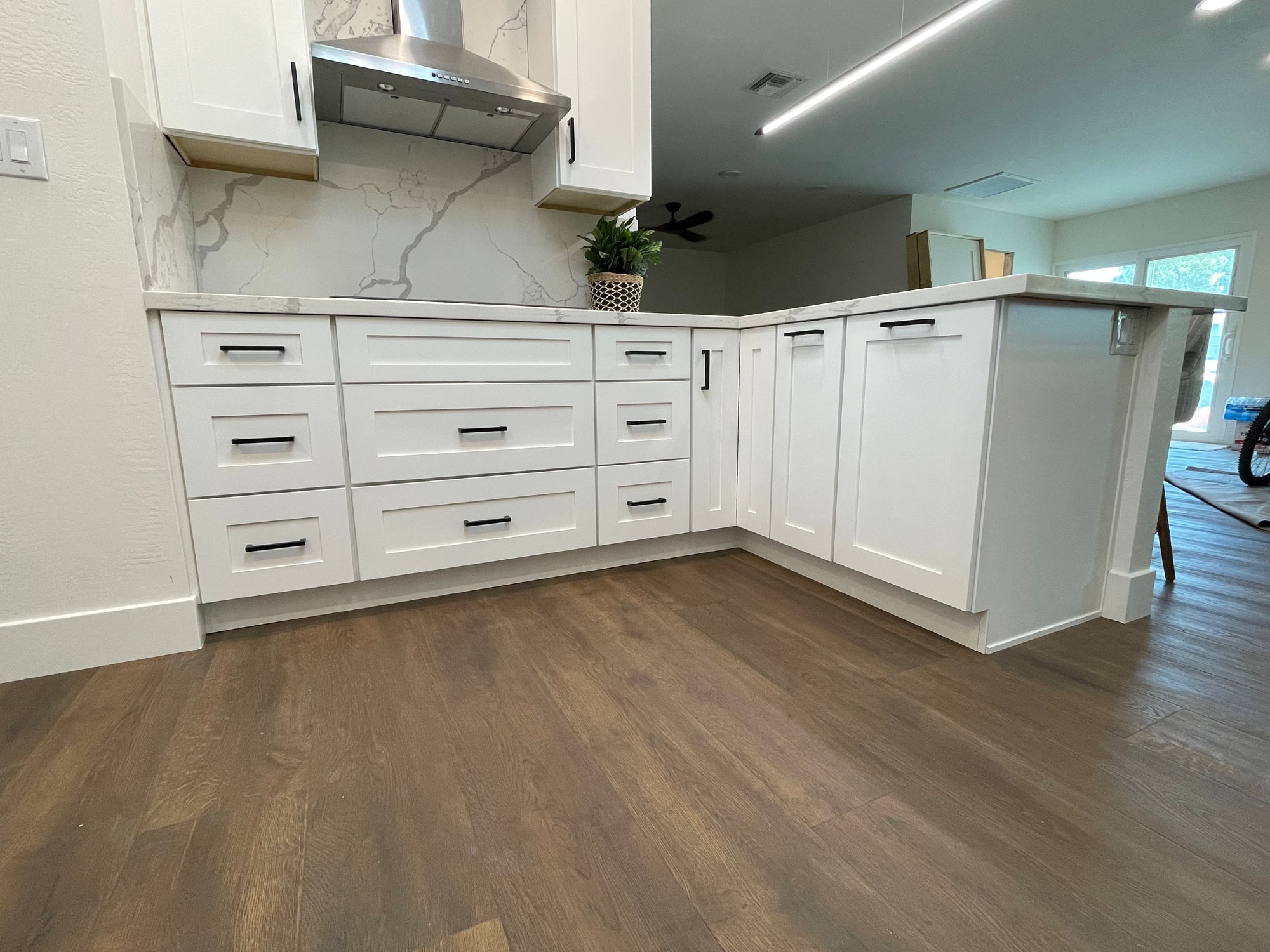 Chandler kitchen — close-up of the drawer stack below the cooktop showing the storage capacity added in the rebuild, with matte black bar pulls on every drawer