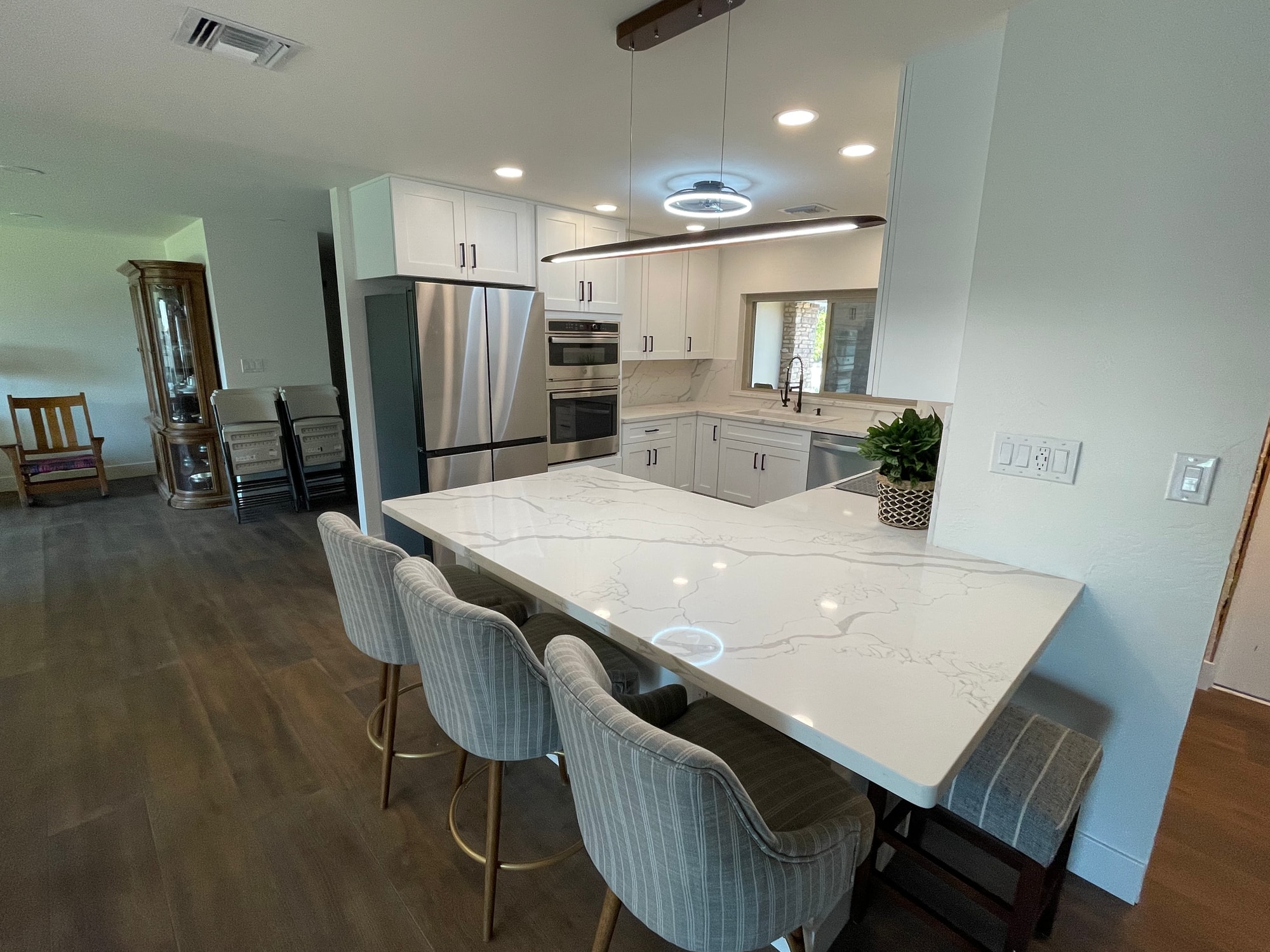 Chandler kitchen — view from the end of the peninsula showing the Calacatta Divine quartz top, bar seating, and open-plan layout the rebuild opened up