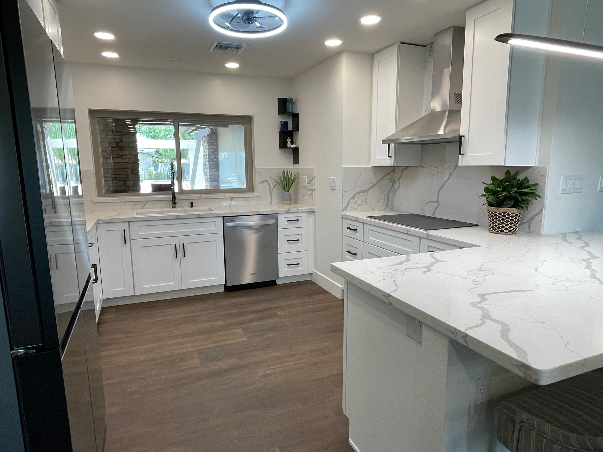 Chandler kitchen — sink wall with matte black pulldown faucet, under-counter dishwasher, Sollid Three Series Shaker White cabinetry, full-height Della Terra Calacatta Divine backsplash, and 7-foot LVP flooring
