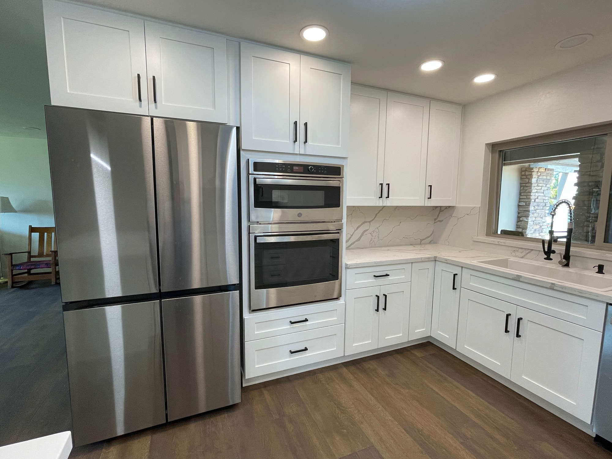 Chandler kitchen — four-door stainless steel refrigerator next to a built-in double wall oven with Calacatta Divine quartz carried continuously across the backsplash