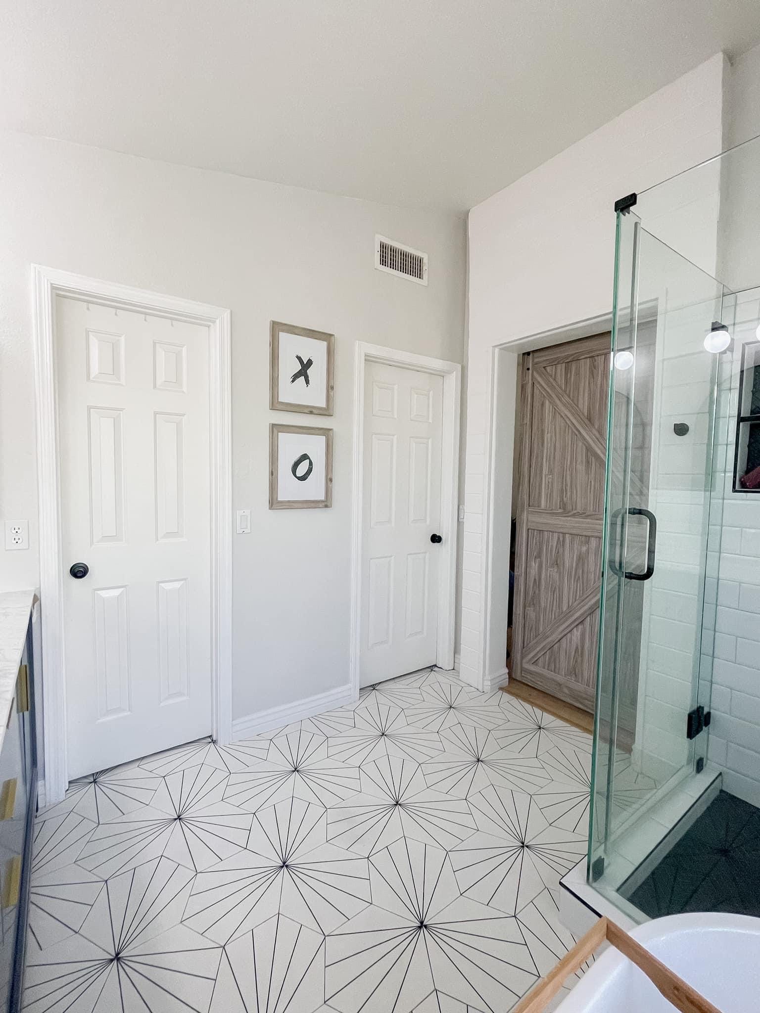 Gilbert master bathroom — entry view showing the starburst floor pattern, framed art, and barn door access to the bedroom