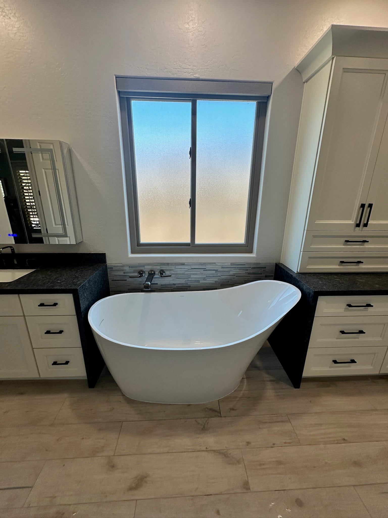 Gilbert master bathroom after — sculptural freestanding slipper tub set against a new low-iron frosted glass window with mosaic tile backsplash