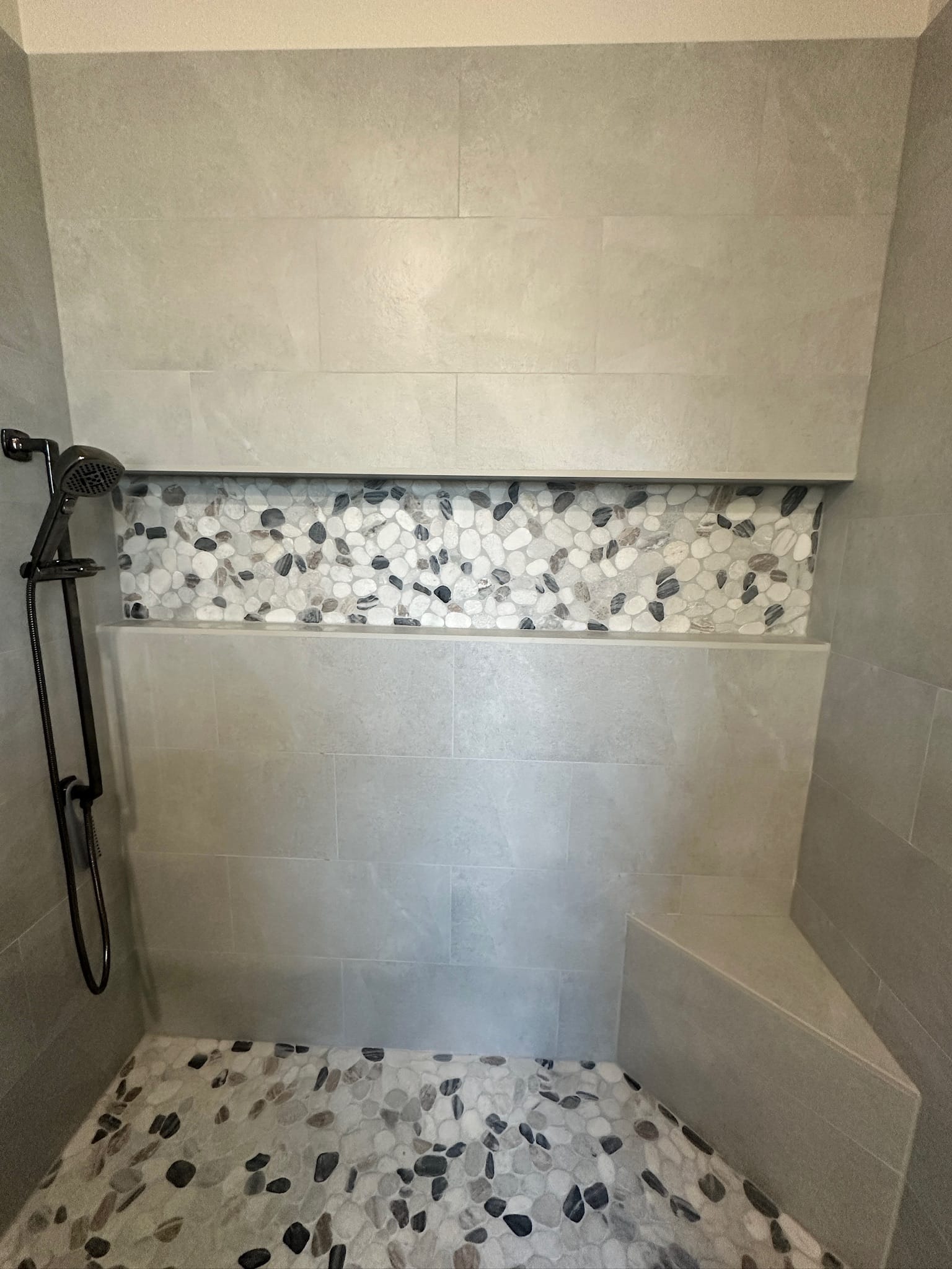 Gilbert bathroom — walk-in shower niche detail with sliced-pebble mosaic accent and matching pebble mosaic floor