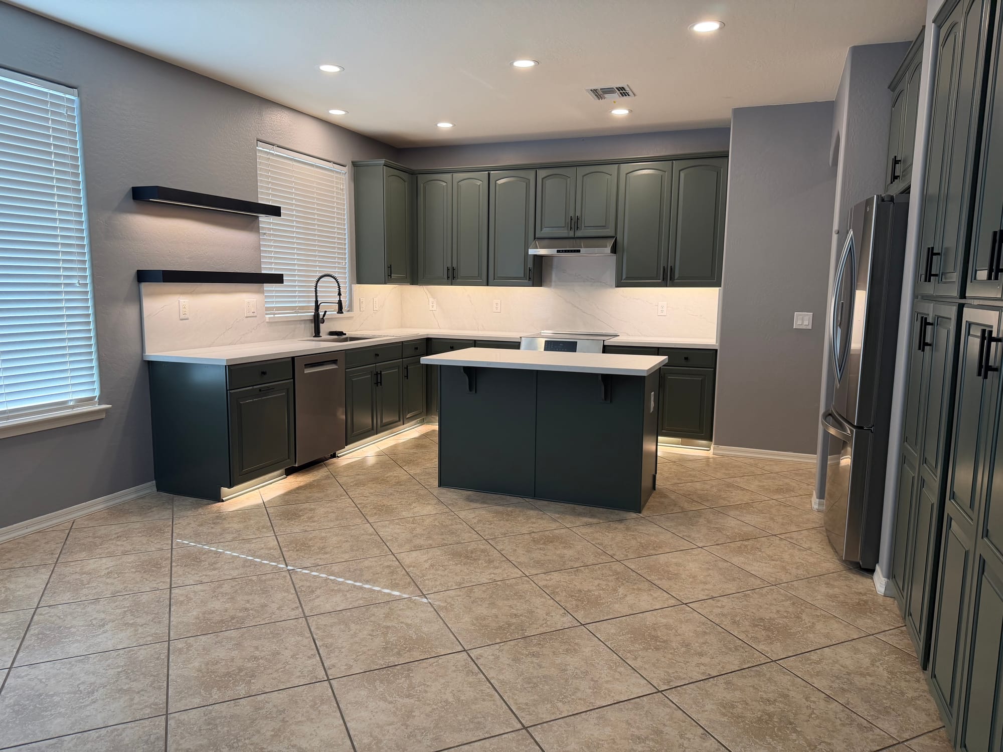 Gilbert kitchen after — sink area with sage cabinets, new black pull-down faucet, white Della Terra quartz, and stainless dishwasher