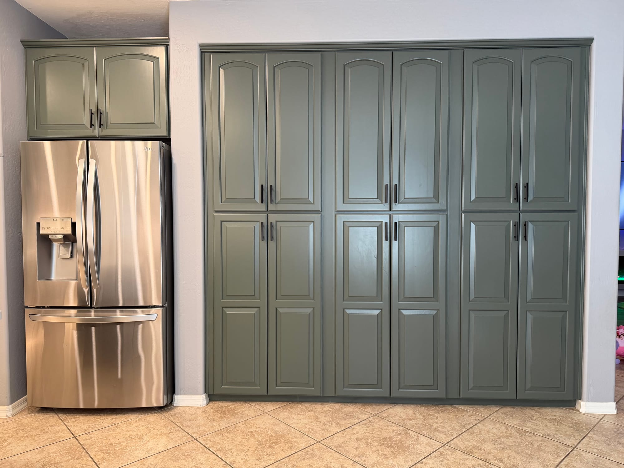 Gilbert kitchen after — full-height sage pantry wall with Sollid roll-out trays behind the doors and stainless French-door fridge