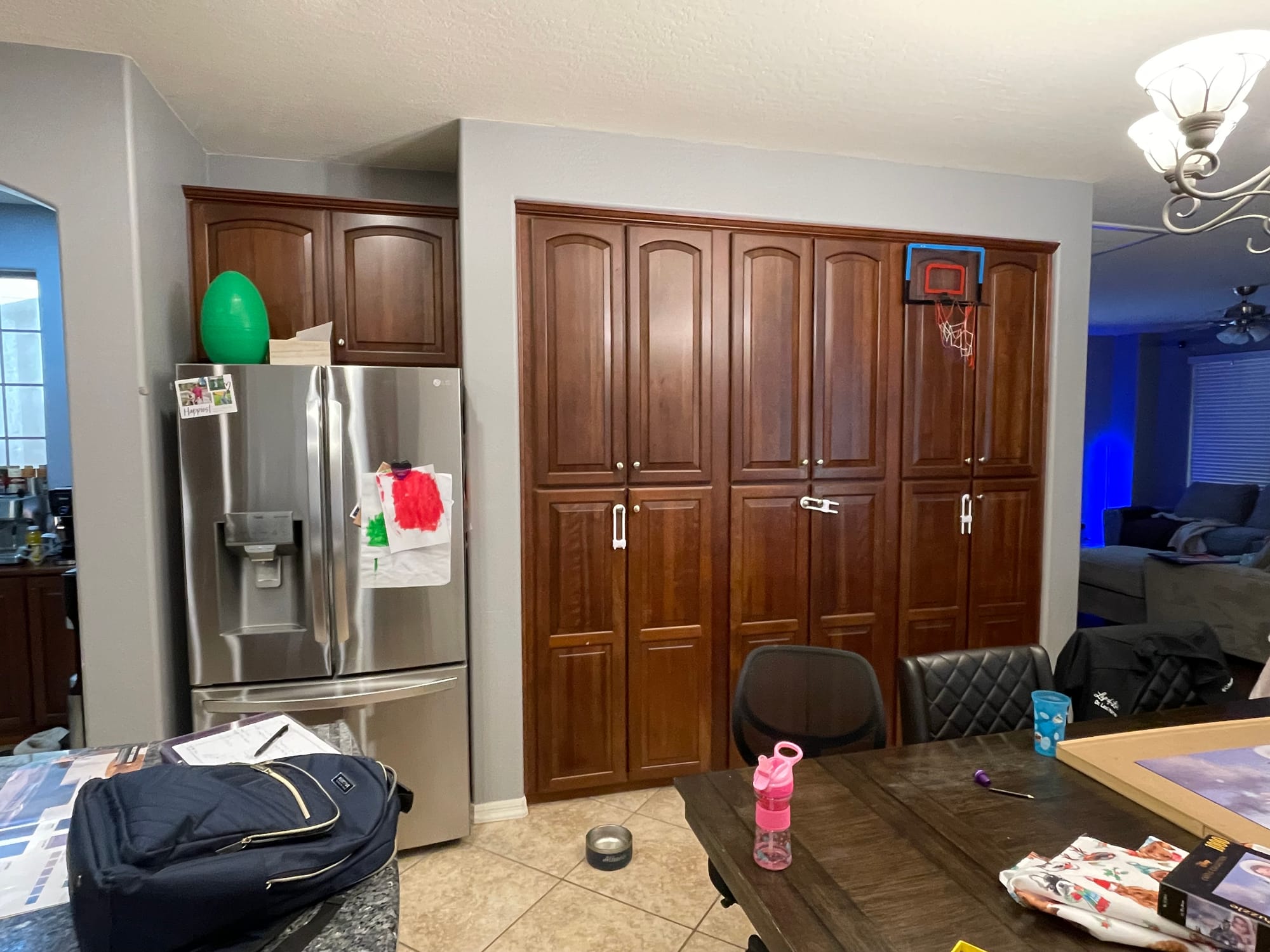 Gilbert kitchen before — original dark cherry raised-panel pantry wall with stainless French-door fridge