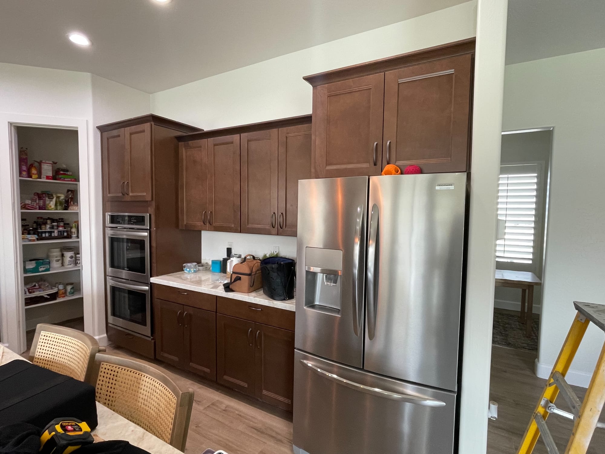 Queen Creek kitchen before update — dark brown shaker cabinets around the double oven, fridge, and pantry
