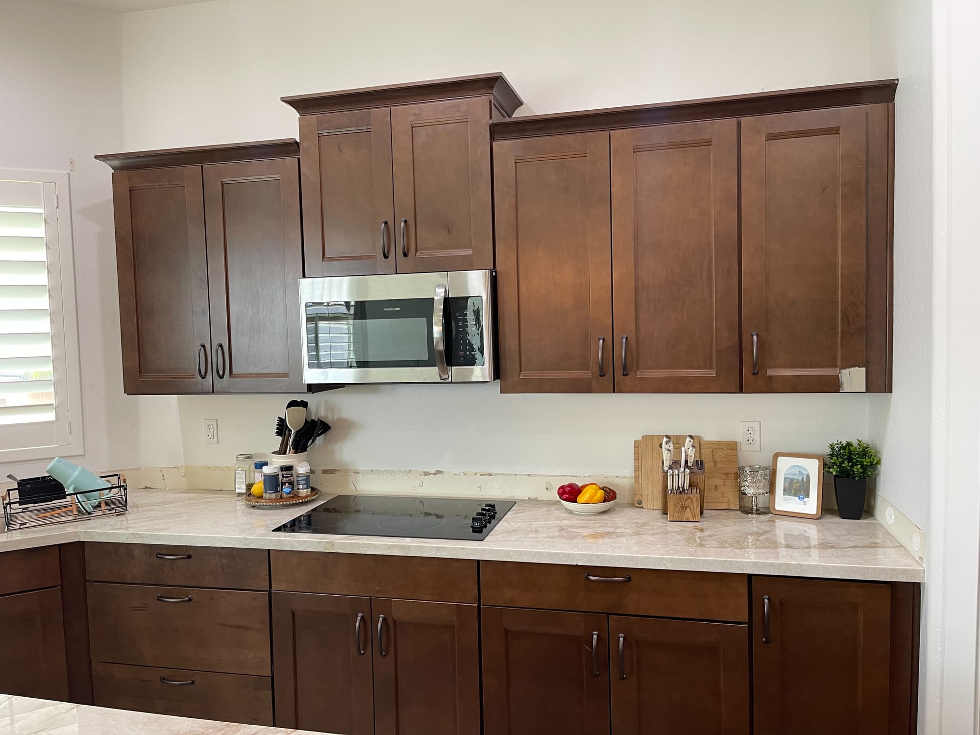 Queen Creek kitchen before — original brown shaker cabinets above the microwave and cooktop