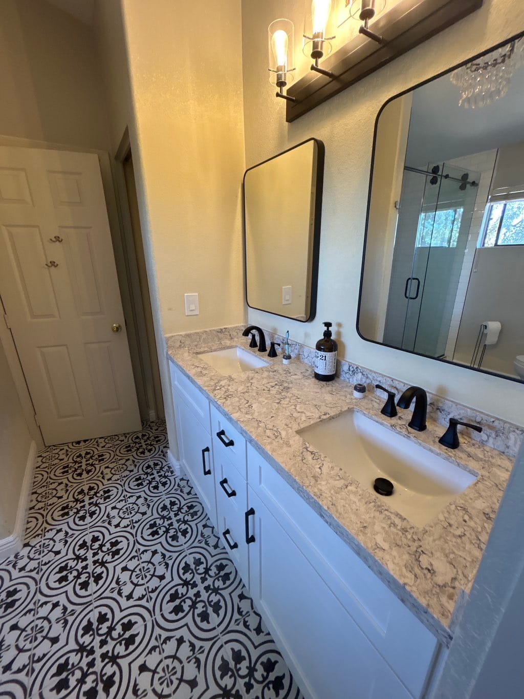 Scottsdale master bathroom after — Sollid 3 Series Shaker White double vanity with marbled quartz countertop, black-framed mirrors, and ornate sconce lighting