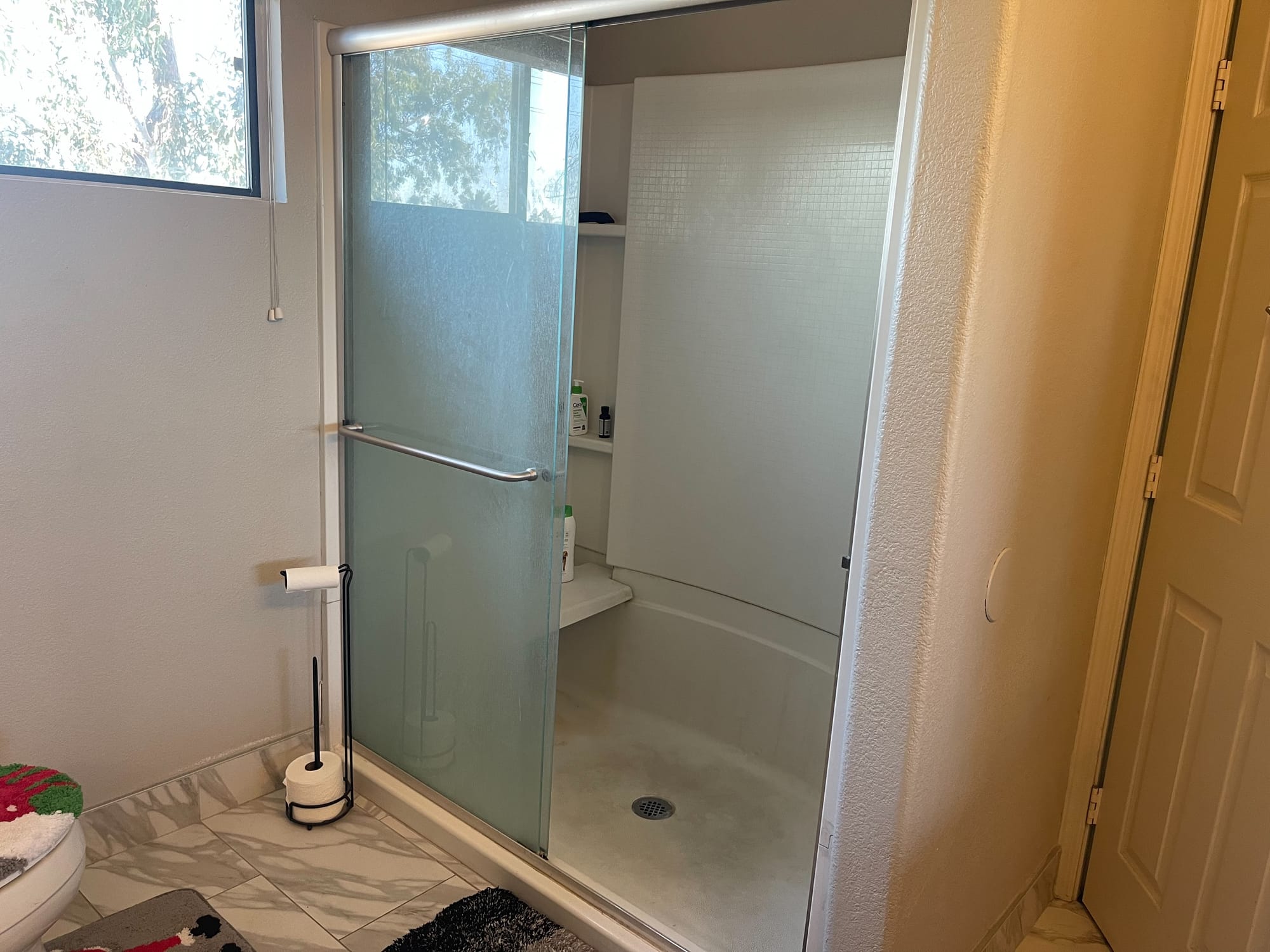 Scottsdale master bathroom before — dated frosted-glass shower stall with beige acrylic walls