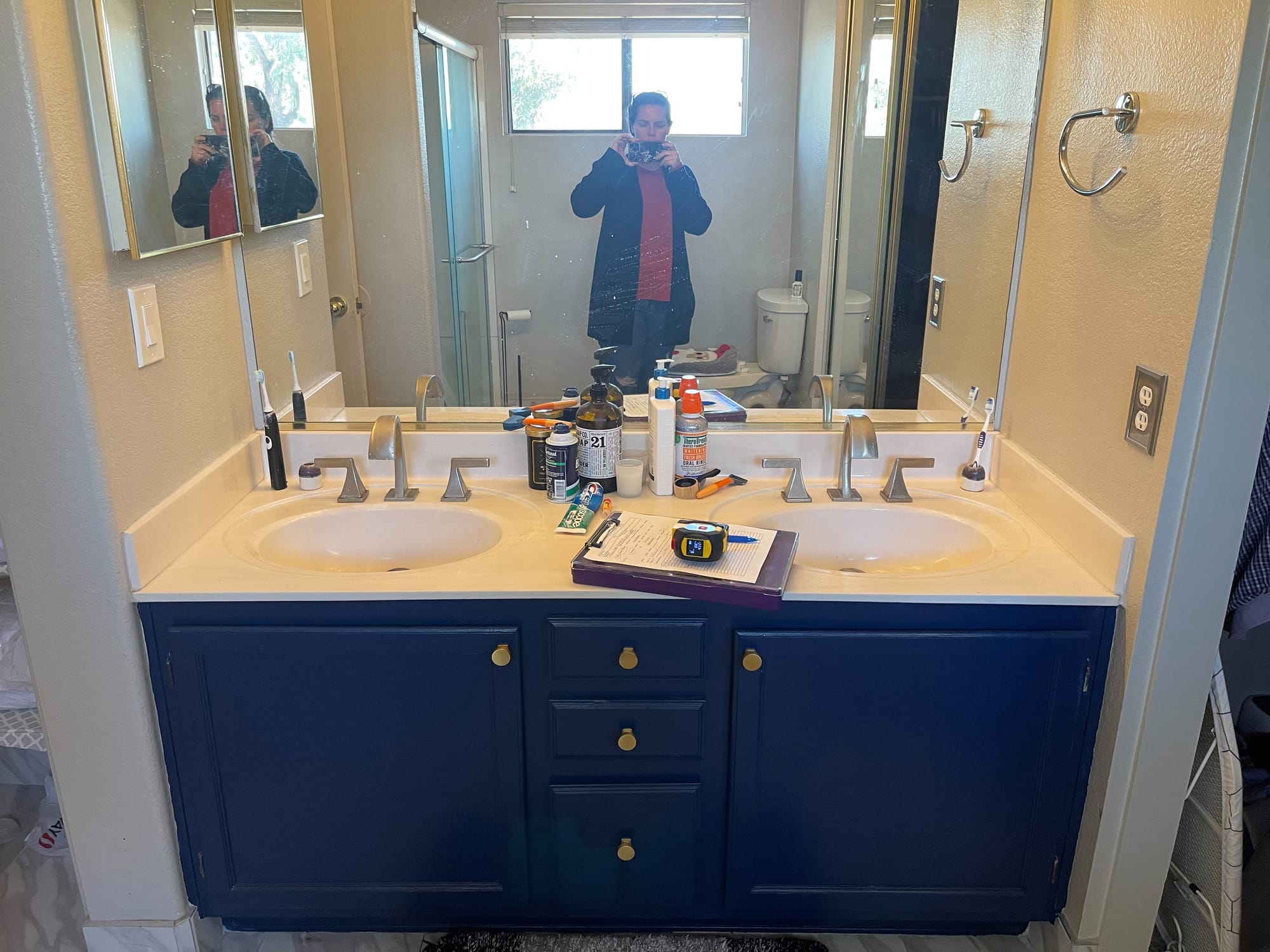Scottsdale master bathroom before — wider view of the dated navy vanity and original marble-look floor tile